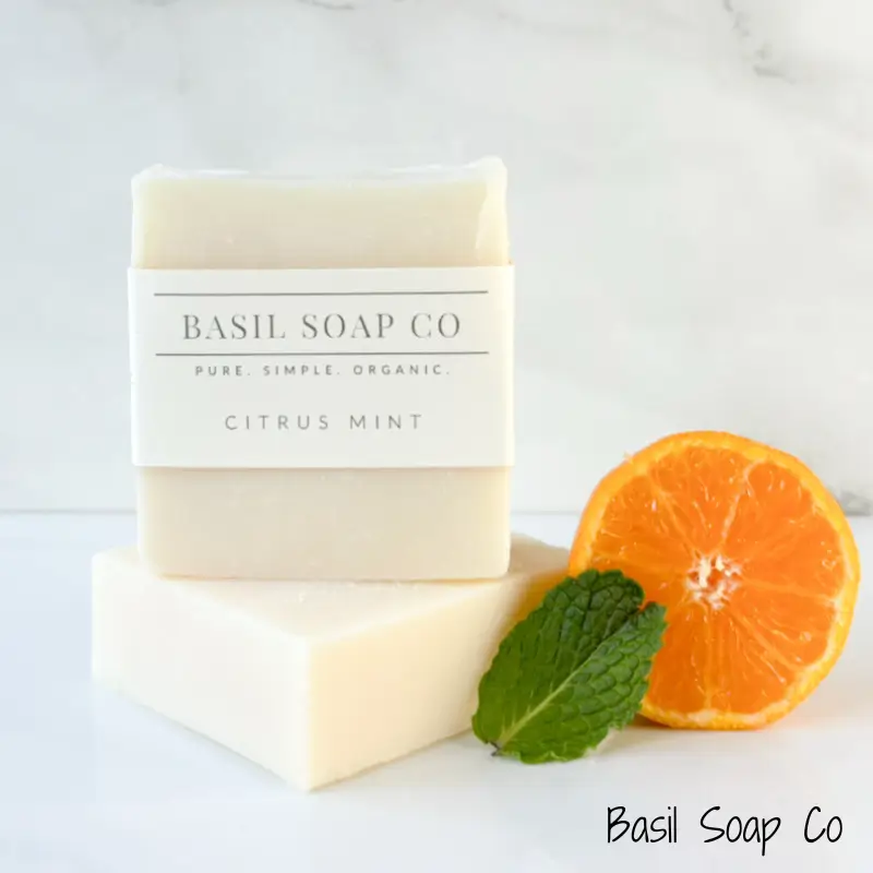 Handmade citrus mint soap next to half an orange and mint leaf